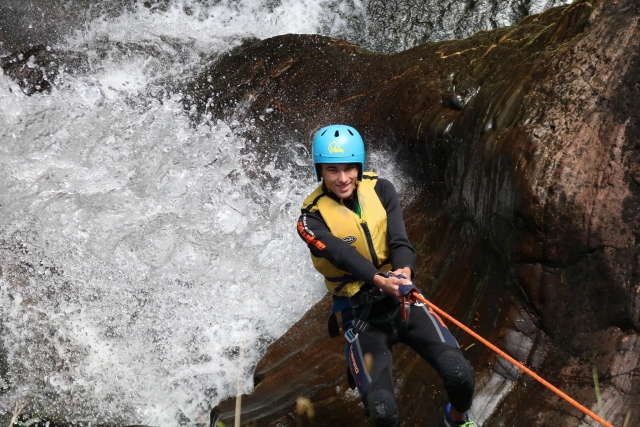 Ragazzo sorridente mentre arrampica durante la sua sessione di canyoning 